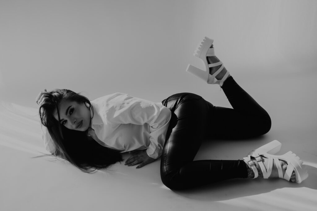 kobieta leży na podłodze ma na sobie buty na grubej szpilce i nogę uniesioną ku górze, sesja kreatywna