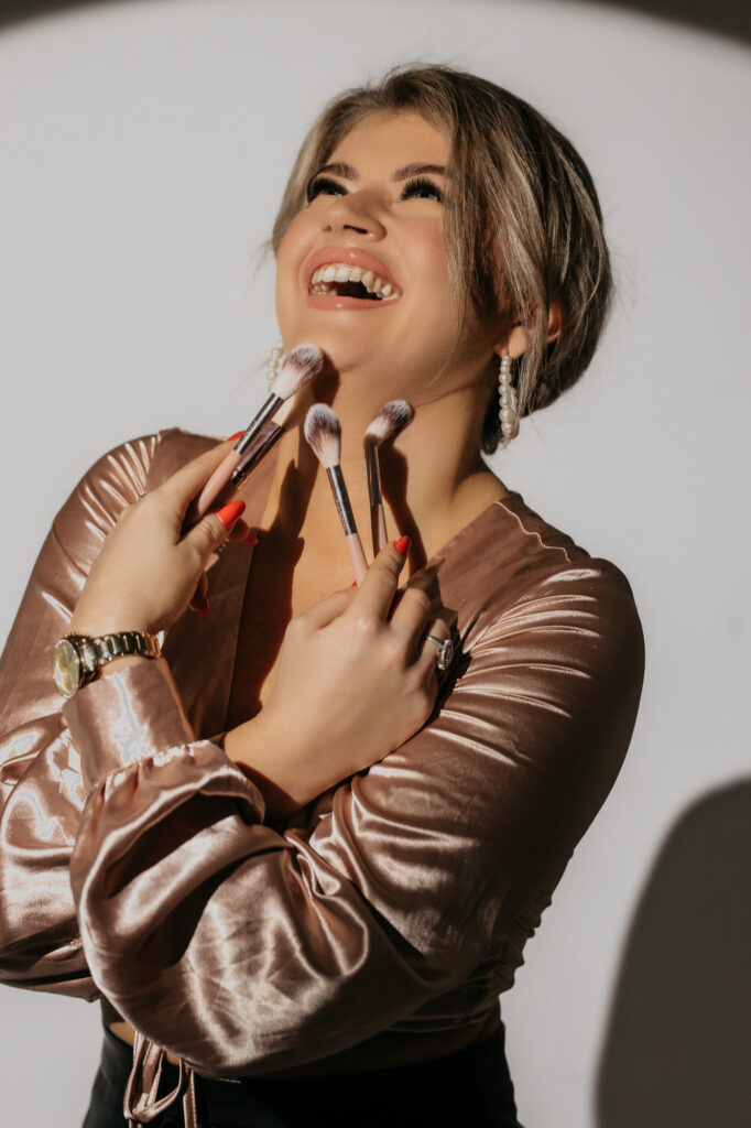 kobieta śmieje się w rękach trzyma pędzle do makijażu