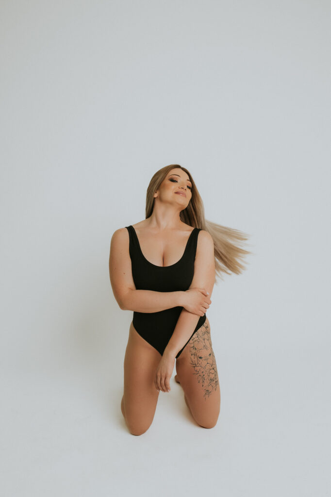 kobieta klęczy vis a vis obiektywu, kręci głową i trzyma się za łokieć