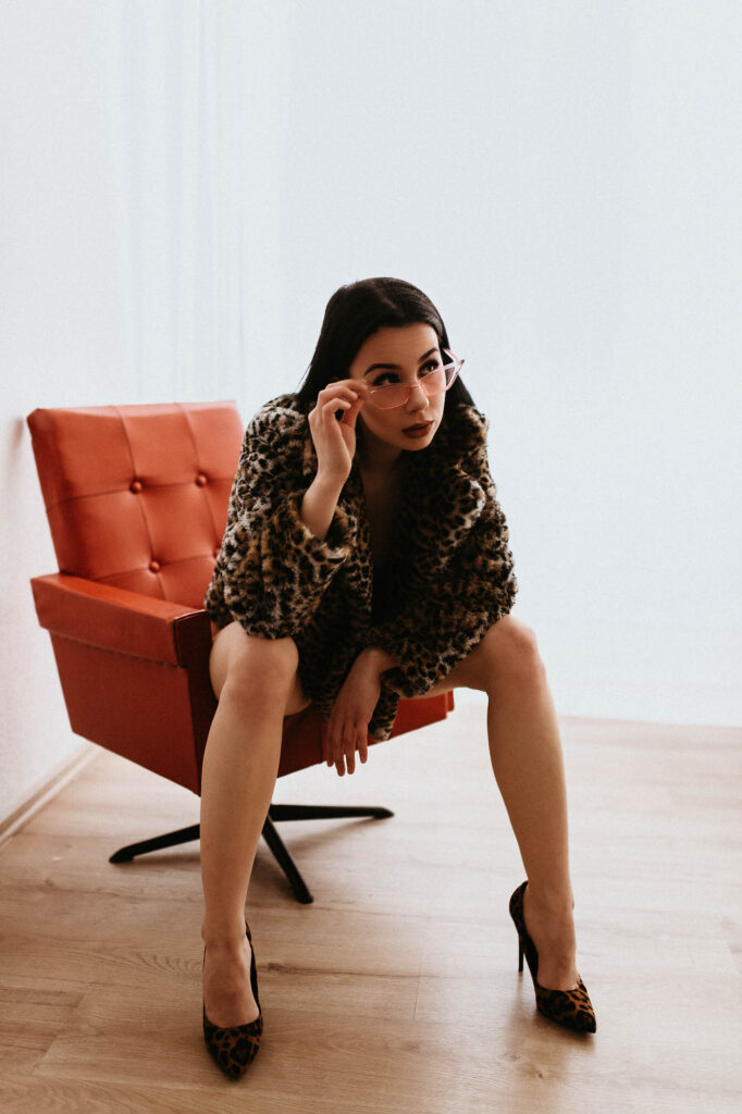 Kobieta w futrze siedzi na czerwonym krześle