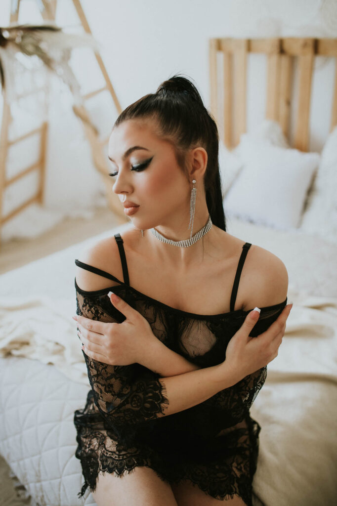 kobieta siedzi na łóżku i trzyma się za ramiona