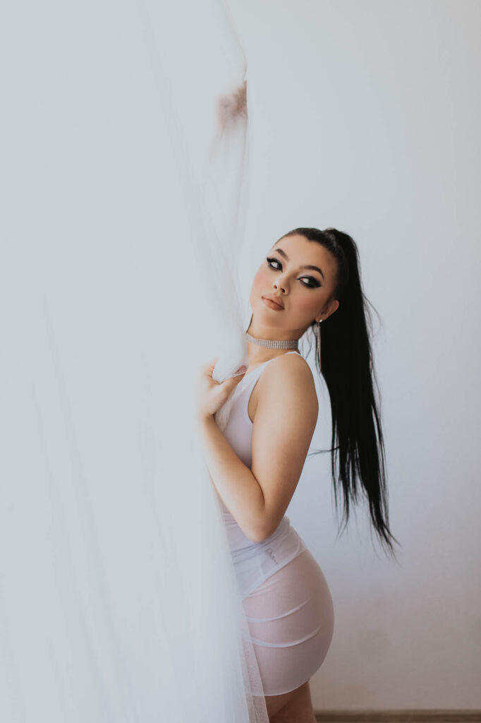 kobieta ubrana na biało stoi przy firance