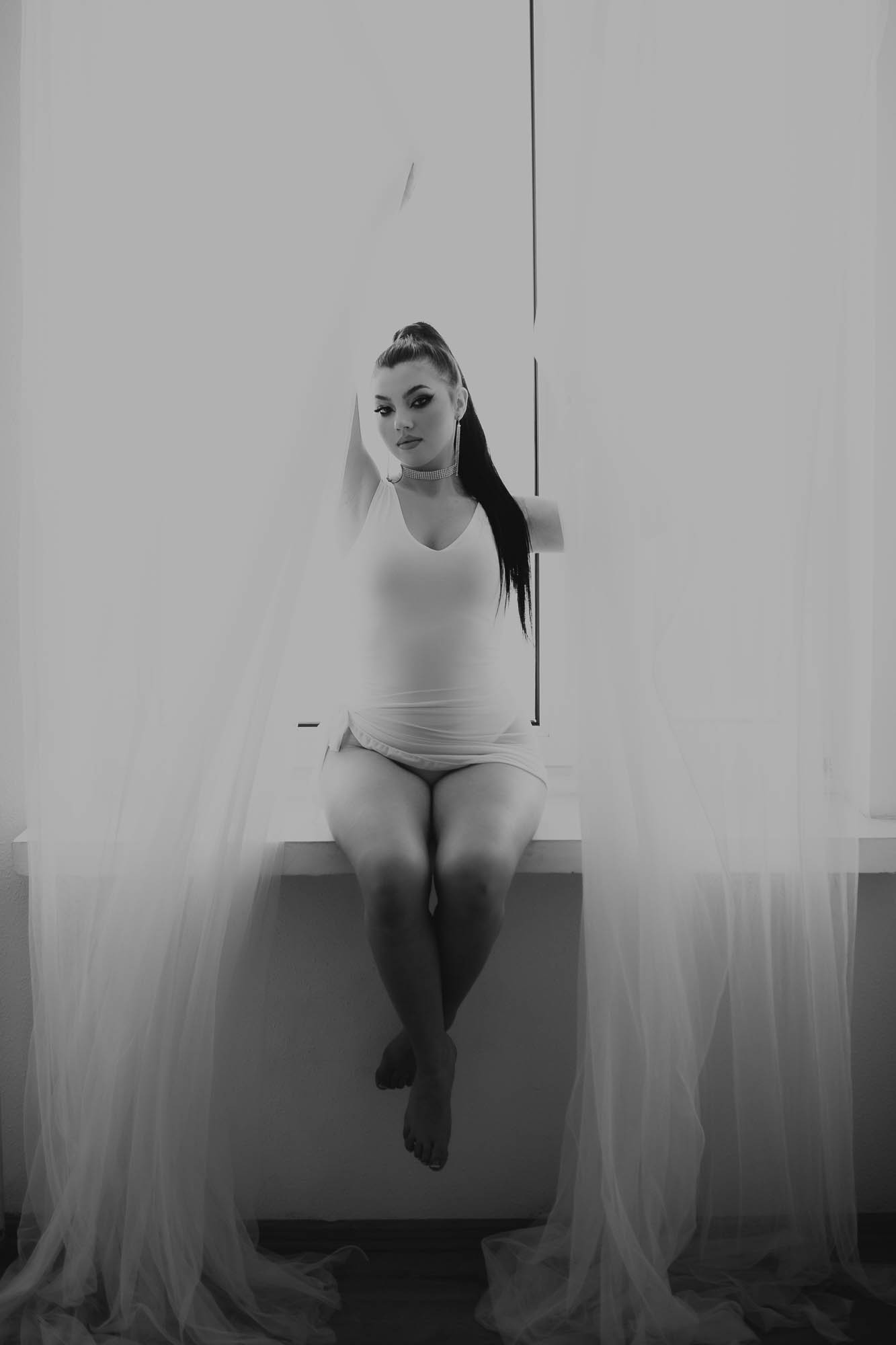 kobieta ubrana na biało siedzi na parapecie