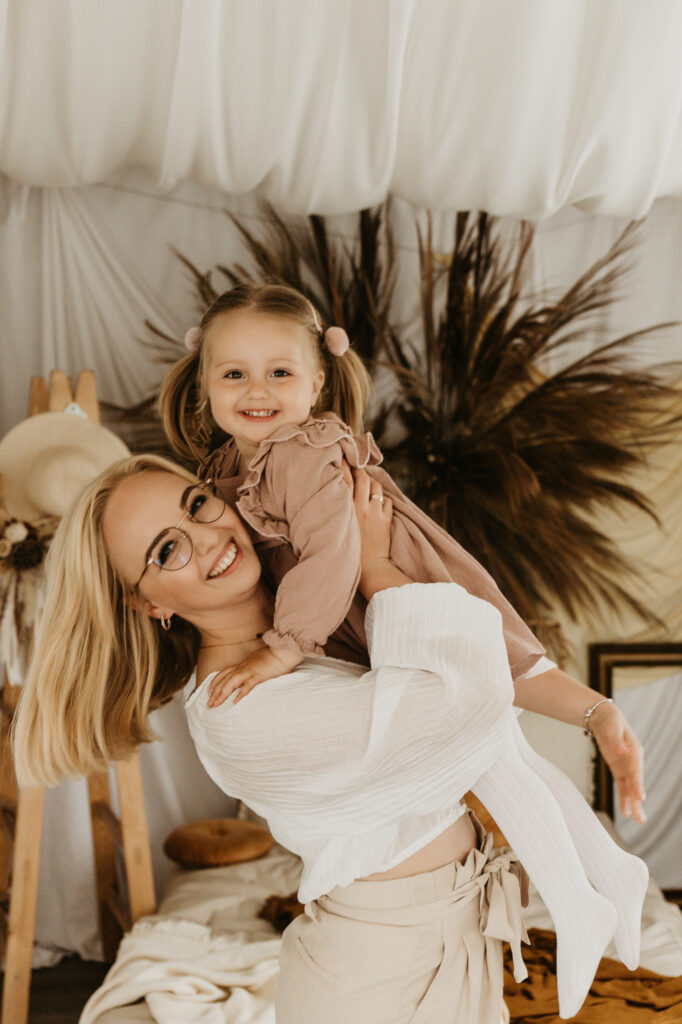 kobieta trzyma córkę na rękach, uśmiechają się