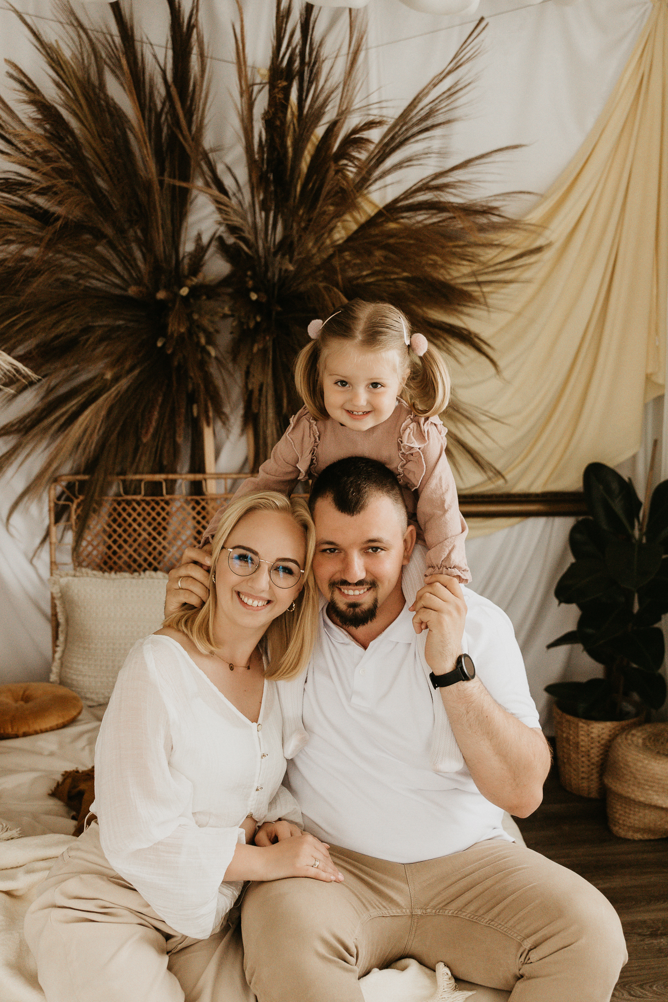 kobieta mężczyzna i dziecko siedzą na łóżku, sceneria boho