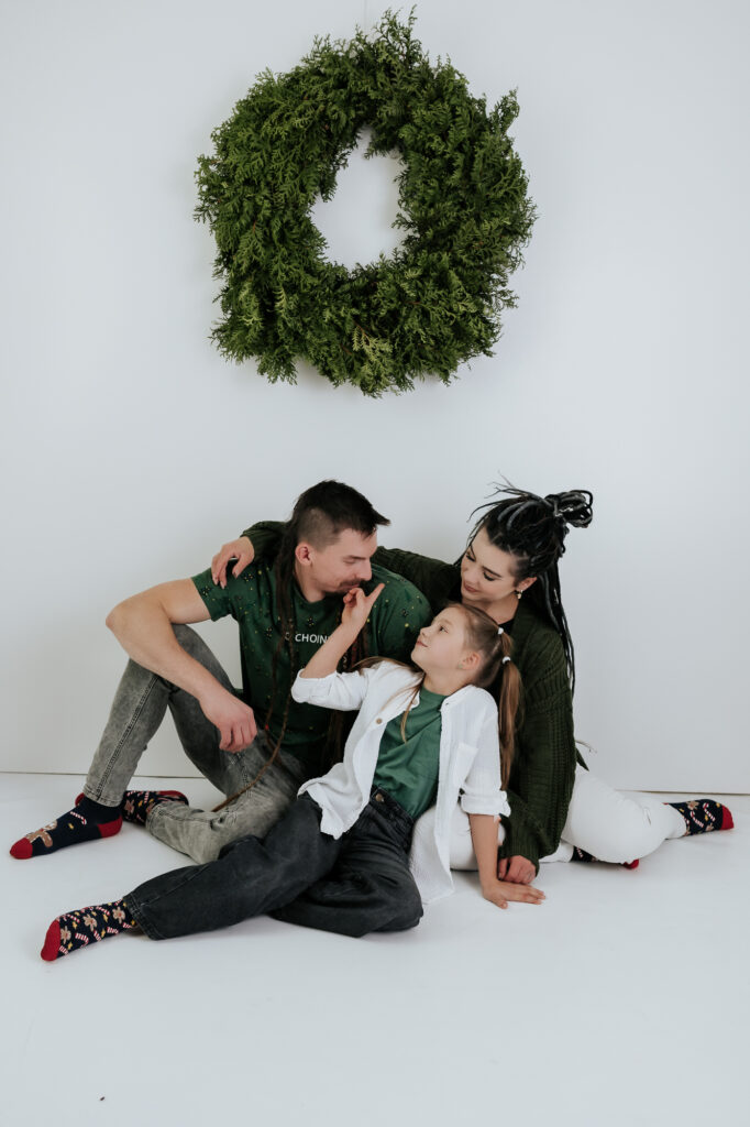 rodzina siedzi na podłodze przytulona mini sesje świąteczne
