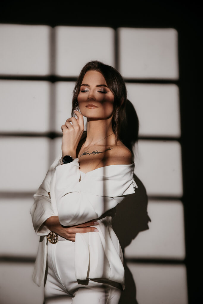 kobieta trzymająca rękę przy brodzie ubrana w biały elegancki strój sesja wizerunkowa