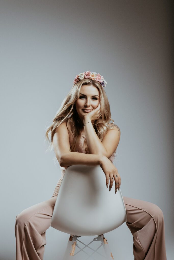 kobieta siedzi na krzesle na oparciu się opiera na glowie ma wianek