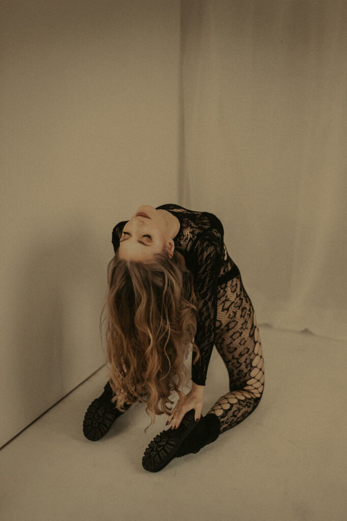 kobieta klęczy na podłodze ubrana na czarno