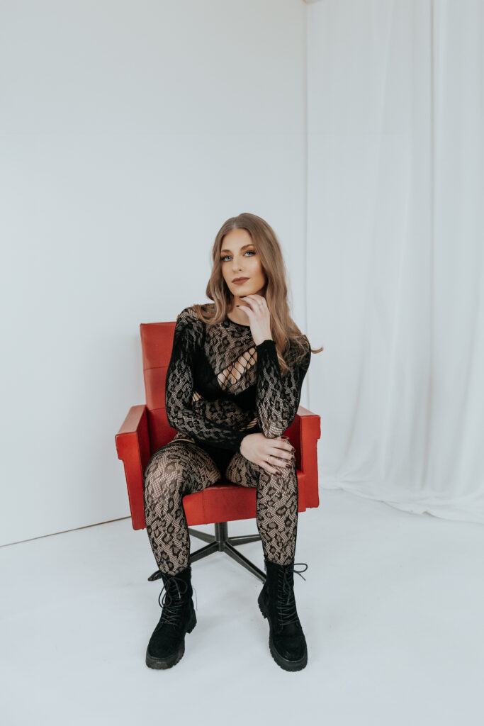 kobieta w czarnym kombinezonie siedzi na czerwonym fotelu