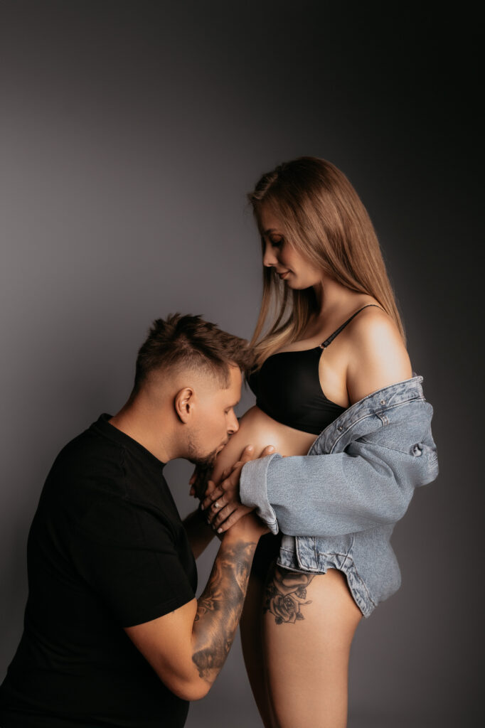 mężczyzna całuje brzuch ciążowy